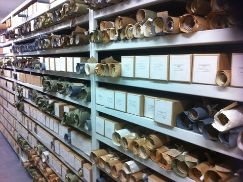 Long archive shelves full of labelled boxes and rolled documents in a records store