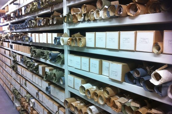 Long archive shelves full of labelled boxes and rolled documents in a records store