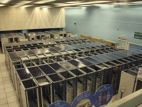 Rows of server racks in a large data centre with pale blue walls